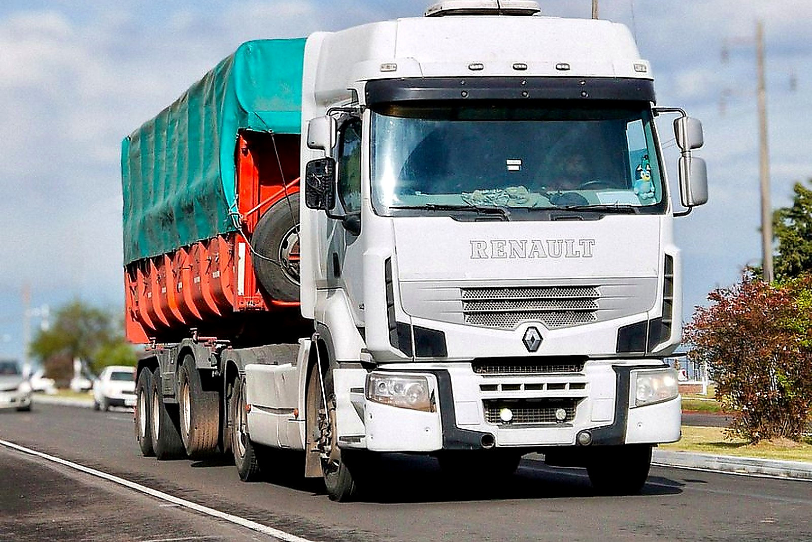 A white cargo truck travels on a highway under a bright blue sky, illustrating transportation and logistics